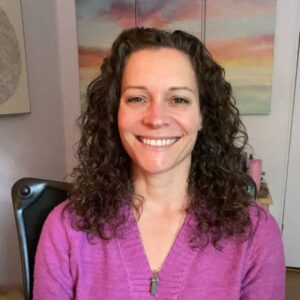 Headshot photo of Julie Cowley smiling in a pink sweater. 