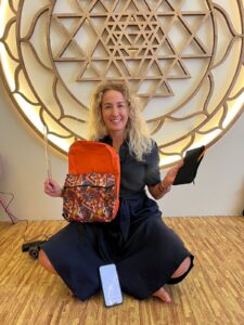 Photo of Sophie Sosa Palazuelos smiling with a large sri yantra wall sculpture behind her.