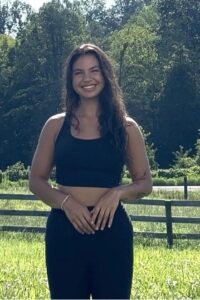 Photo of Haley Bonilla smiling and standing in a green pasture.