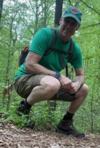 Photo of Jim Keesling hiking in a lush, green forest.